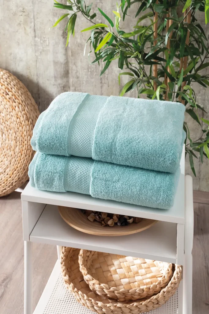 Aqua green Hotel Collection towels folded on a white stool