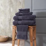 Charcoal Hotel Collection towel set stacked on a wooden stool
