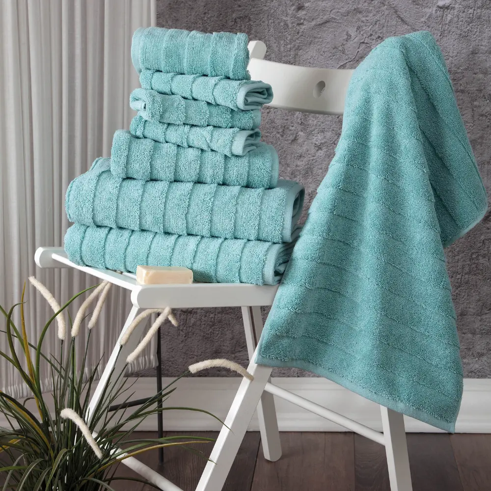 Aqua green Bagno Milano Elegance ladder-stripe towels stacked on a stool with a towel hanging