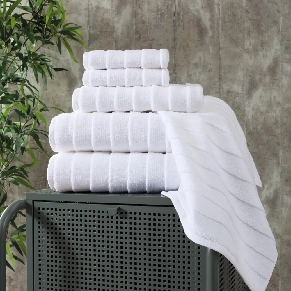 White Bagno Milano Elegance ladder-stripe towels stacked on a stool with a white towel hanging