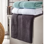 Aqua, white and charcoal Hotel Collection towels stacked on a stool