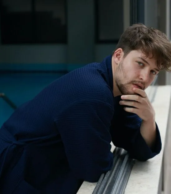 Man in a navy waffle pique spa robe relaxing by a window