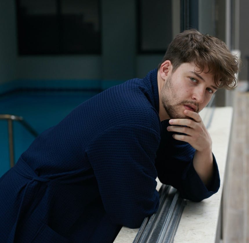 Man in a navy waffle pique spa robe relaxing by a window