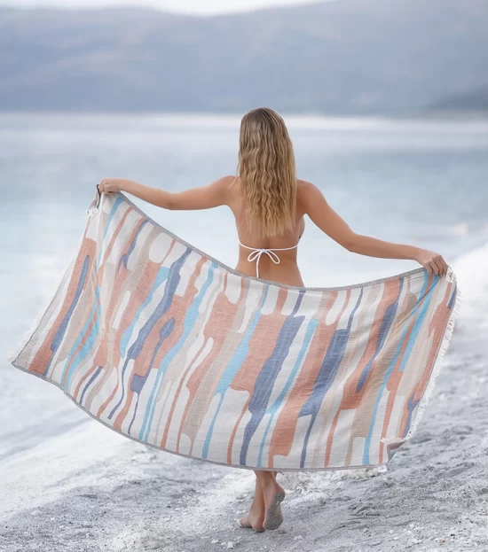 Woman holding the Electra Peshtemal Towel open on the beach