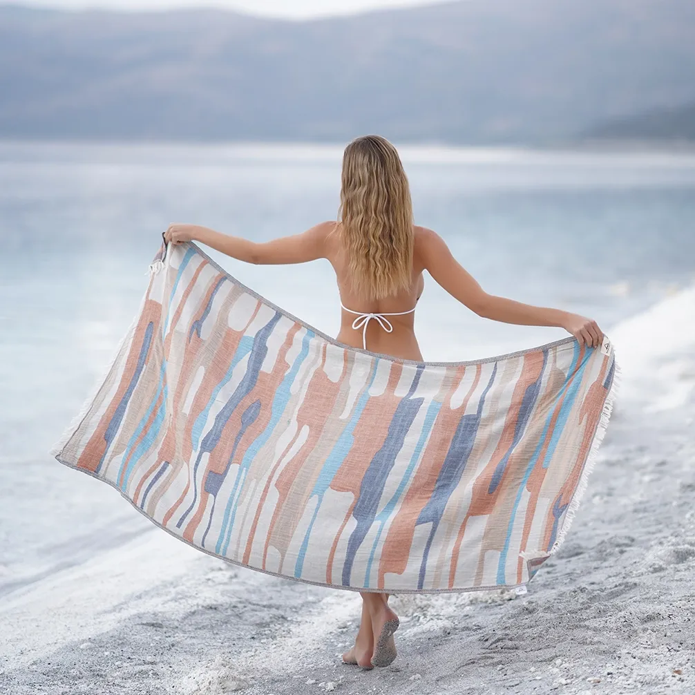 Woman holding the Electra Peshtemal Towel open on the beach