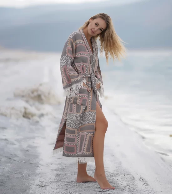 Woman wearing the Lich Peshtemal Bathrobe on a white beach