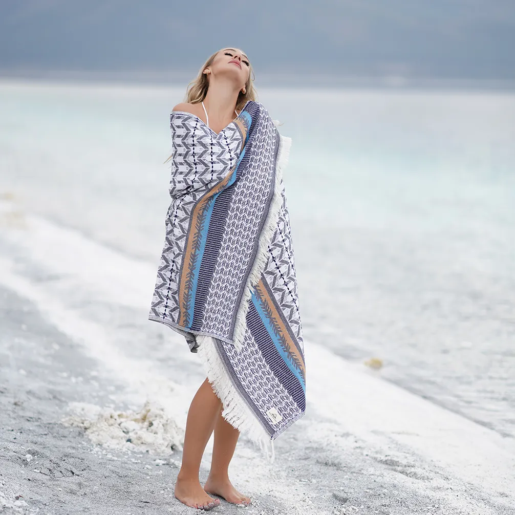 Woman wrapped in the blue Myra Peshtemal Towel on the beach