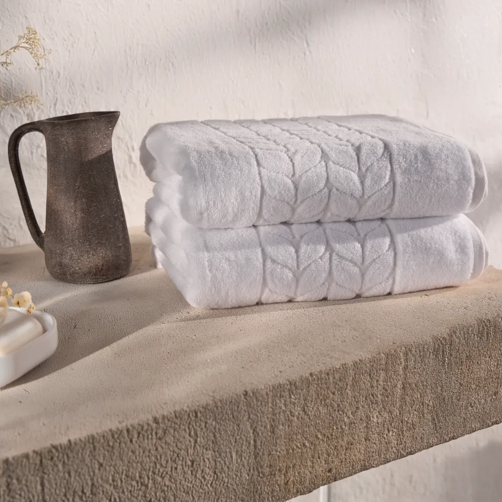 White organic jacquard border bath towels folded on a shelf