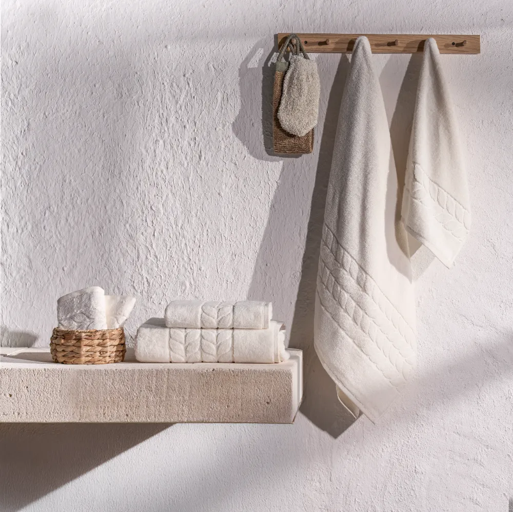 Cream organic jacquard border towels hanging in a bathroom