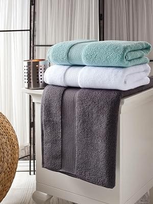 Charcoal and white Bagno Milano Hotel Collection towels stacked on a bathroom shelf