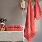 Coral jacquard border towels hanging on hooks with a folded stack in a basket - Bagno Milano