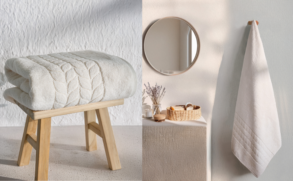 Folded white jacquard border towel and hanging towel by a round mirror - Bagno Milano