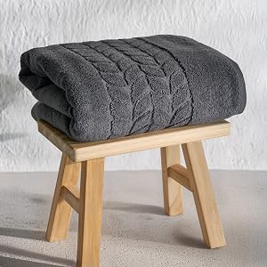Folded charcoal gray jacquard border towel on a wooden stool - Bagno Milano