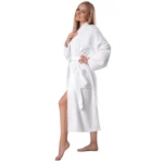 Side view of a woman in a white terry cotton robe with a patch pocket and self-tie belt