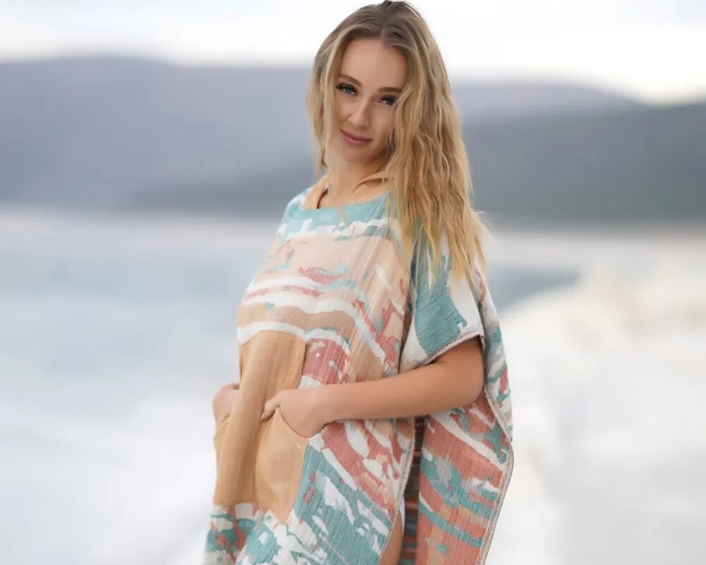 Woman wearing the Bagno Milano Vega peshtemal poncho by the water