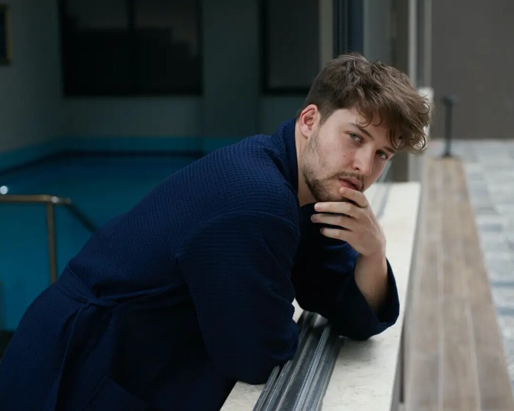 Man in a navy Bagno Milano waffle pique spa robe by the pool